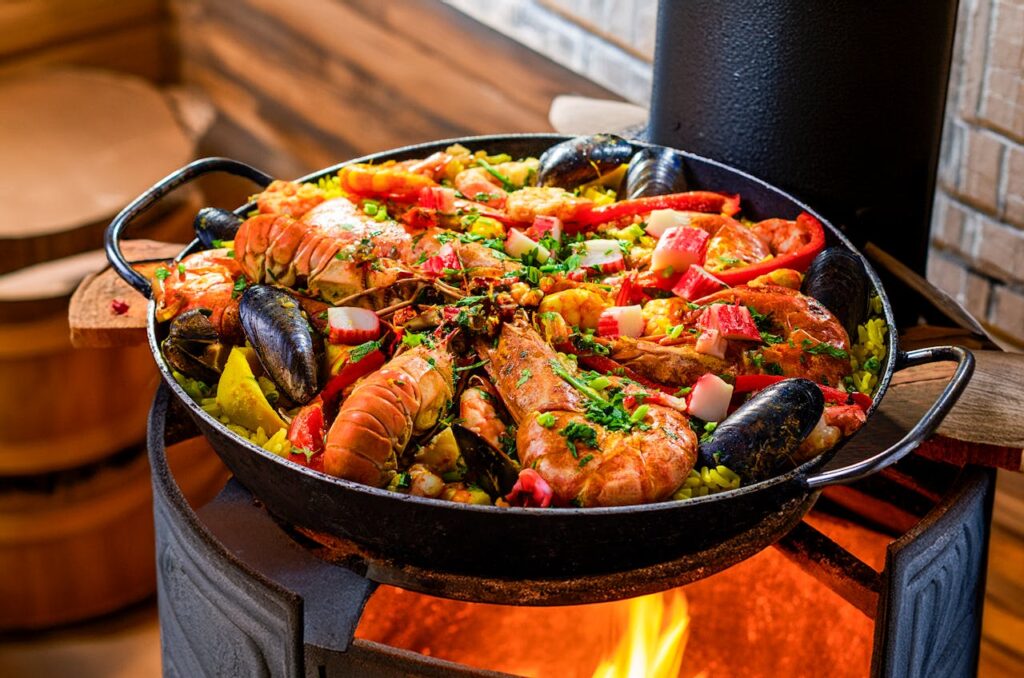 pexels photo 30488931 Delicious seafood paella sizzling atop an open flame, filled with colorful ingredients.